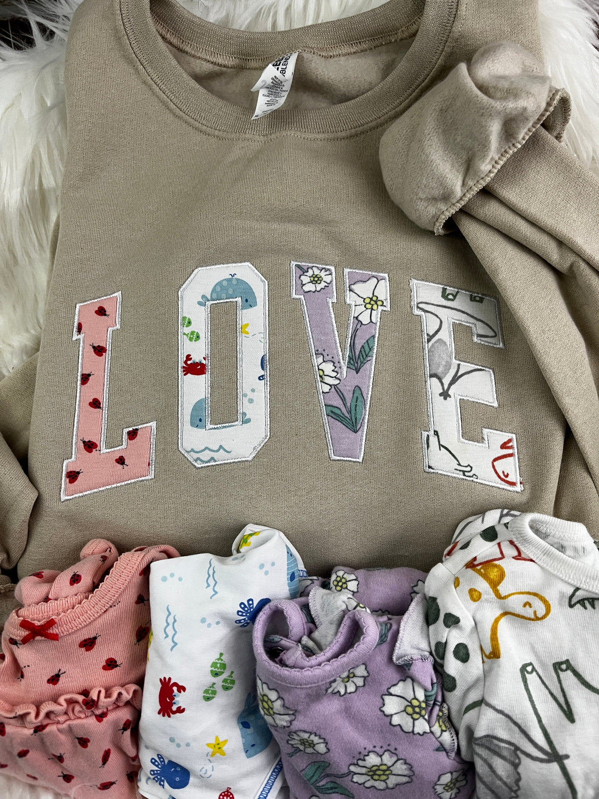 Curved love keepsake sweatshirt appliqued from baby clothes - design close up