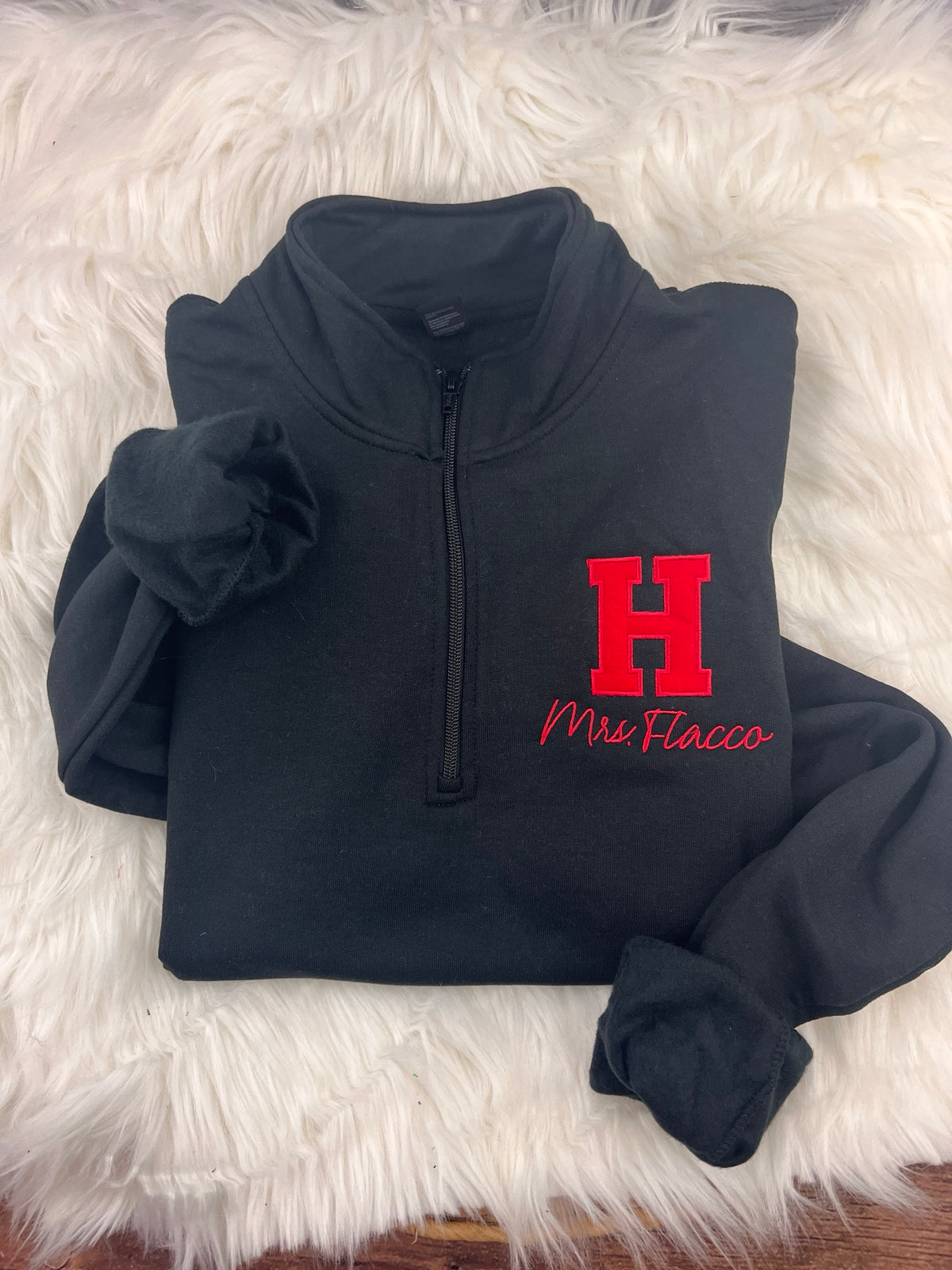 Applique H quarter-zip with teacher name, folded