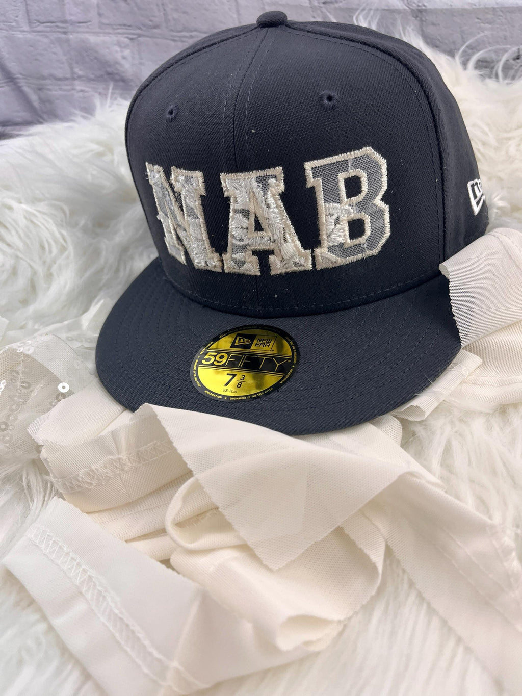 Angled view of the wedding dress keepsake hat showing the applique detail